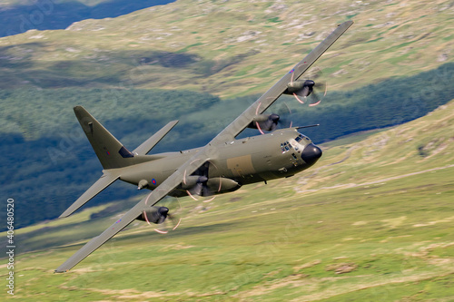 RAF (Royal Air Force) Green camouflage Lockheed C-130 Hercules transport flying low level in the United Kingdom.  photo