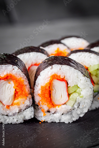 appetizing sushi roll futomaki with cucumber crab stick and masago on a black stone plate