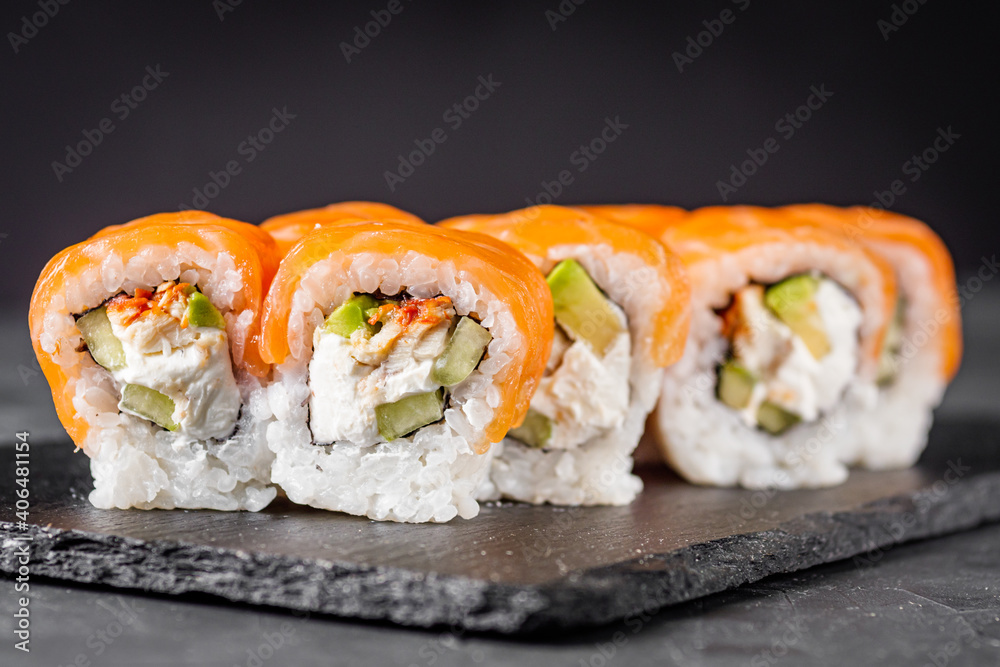 appetizing sushi roll philadelphia with avocado cheese eel cucumber and salmon on a black stone plate appetizing sushi roll philadelphia with avocado cheese eel cucumber and salmon on a black stone plate