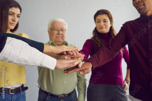 Cropped image of a group of co-workers of different ages and nationalities folds their arms as a symbol of cooperation. Concept of unity and teamwork. Selective focus. © Studio Romantic
