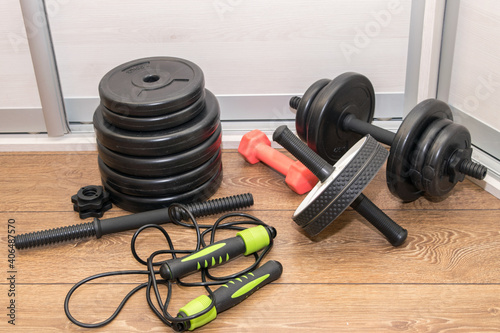 A home gym, dumbbells, ab roller, skipping rope on the wooden floor