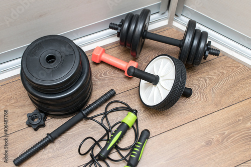 A home gym, dumbbells, ab roller, skipping rope on the wooden floor