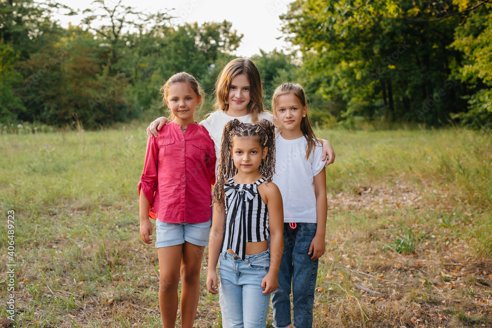 Fototapeta premium A group of cheerful girls are smiling and playing in the Park during sunset. Children's summer camp