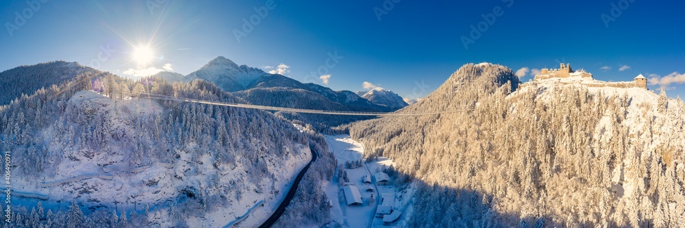 pedestrian suspension bridge over hermitage and ruin ehrenberg in reutte in the snow-covered winter with sunbeams