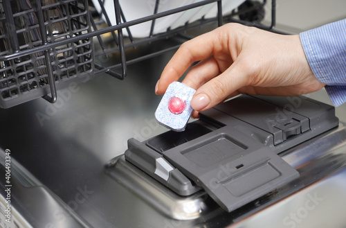 Female hand putting detergent into the dishwasher machine photo