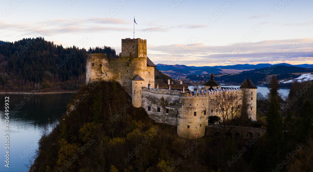 Scenic view of ancient fortified Dunajec Castle on top of hill above Czorsztyn lake in Polish city of Niedzica at dusk..