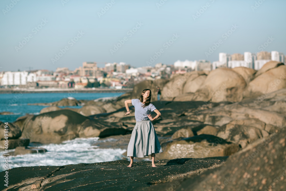 The dancer woman is engaged in choreography on the rocky coast of the ocean.