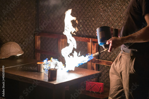 The waiter prepares coffee on the client's desk using fire.