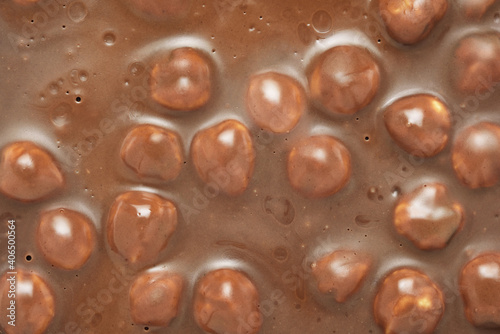 Brown milk chocolate bar with whole hazelnuts background.