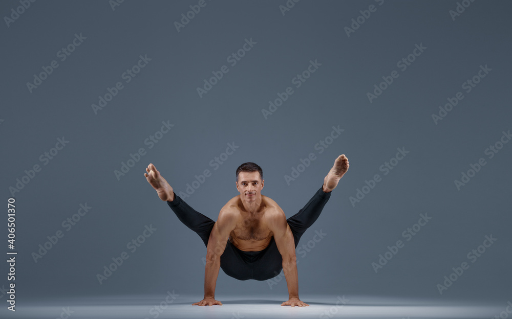 Fototapeta premium Male yoga doing stretching exercise in studio