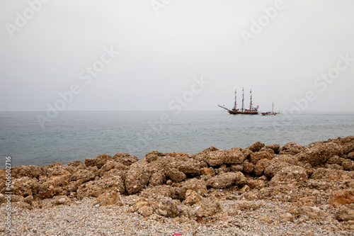 Sailboat in the sea near the rocky coast