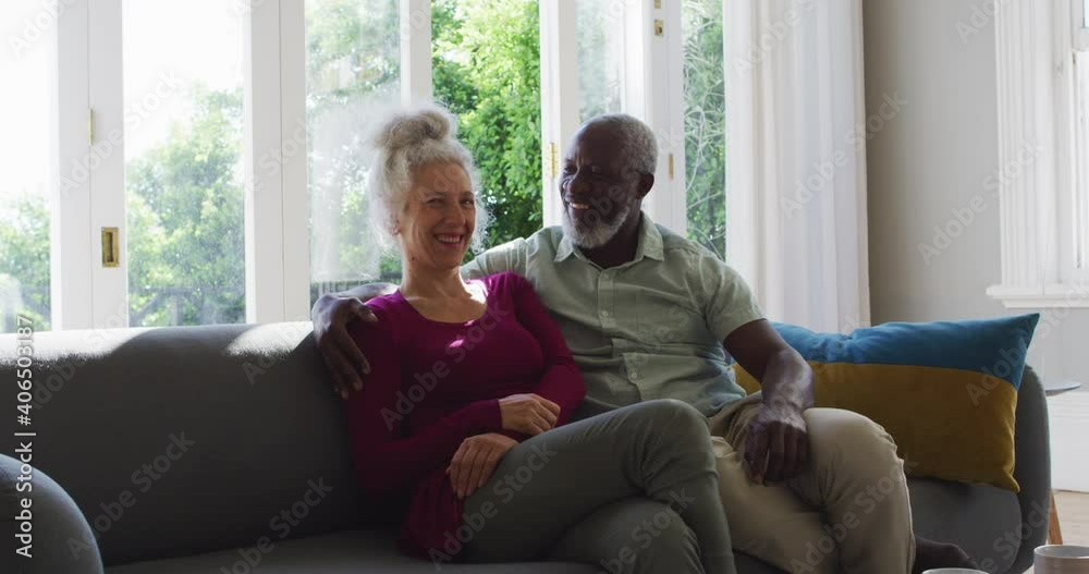 Portrait of mixed race senior couple smiling while sitting on the couch at home Portrait of mixed race senior couple smiling while sitting on the couch at home