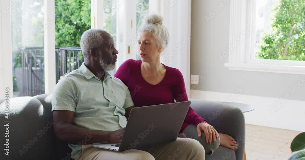Mixed race senior couple using laptop in the living room at home Mixed race senior couple using laptop in the living room at home