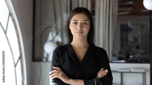 Head shot portrait confident Indian businesswoman hr manager standing in modern office with arms crossed, serious entrepreneur team leader mentor posing for corporate photo, looking at camera photo