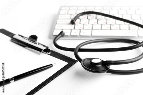 Stethoscope, pen, clipboard and keyboard on white background. Medical concept. Closeup.