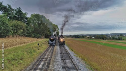 Aerial View of 2 Restored Antique Steam Engines and Passenger Cars Steaming Up at a Small Rail Road Station