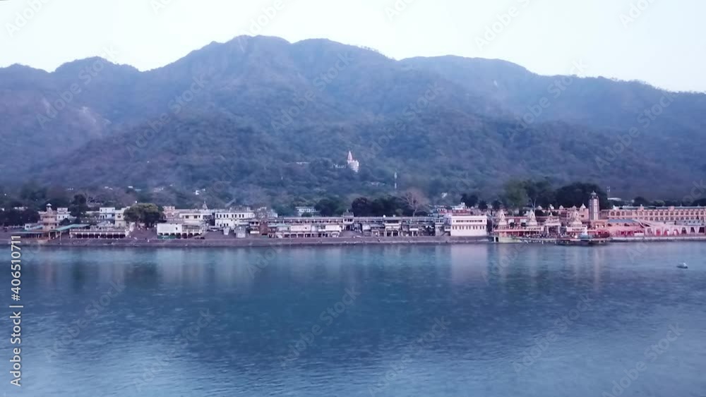 Calm Water With Historic Structures At Ganges River In Ramjhula Rishikesh India With Ridges Background. - Aerial Drone Pullback Calm Water With Historic Structures At Ganges River In Ramjhula Rishikesh India With Ridges Background. - Aerial Drone Pullback