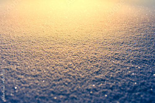 Snow texture in cold night time lighten by the bright orange light. Winter season background. Winter season and snowfall concept.