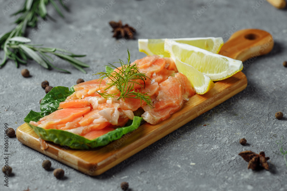 Pieces of fried salmon with dill and lemon wedges on a wooden board Pieces of fried salmon with dill and lemon wedges on a wooden board