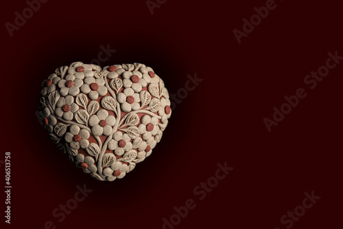 Heart shape with flowers sewed on it isolated on a dark background