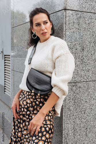 Young elegant girl posing at city street. Pretty beautiful business woman in elegant dress against city background.