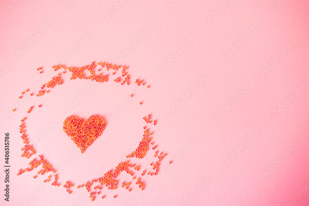 Composition of the heart as a symbol of love laid out from red beads on pink background for valentine's day.