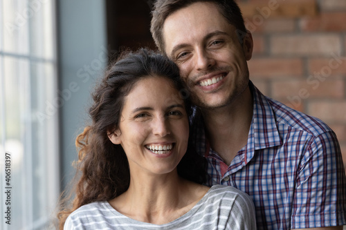 Close up portrait of happy millennial couple renters or tenants pose in new home moving together. Smiling young Caucasian man and woman celebrate relocation to own house, relax on weekend.