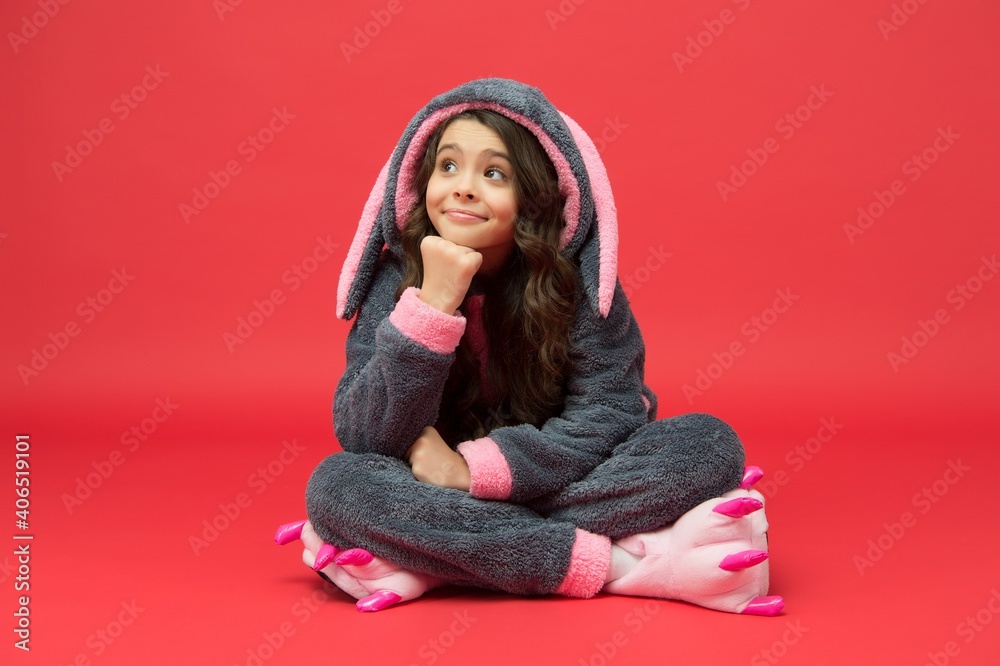 Small kid with cute dreamy look wear bunny pajamas sitting red background, Easter Small kid with cute dreamy look wear bunny pajamas sitting red background, Easter