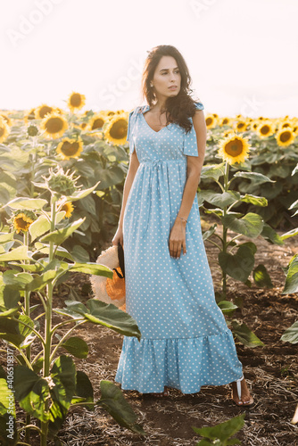 Young beautiful brunette in an elegant summer outfit dress in the rays of the sun on nature walk