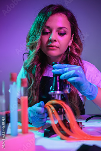 Woman hairdresser colorist examines hair structure using a microscope.