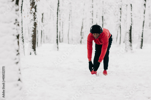 Young african american man doing exercise on winter day in forest © Astarot