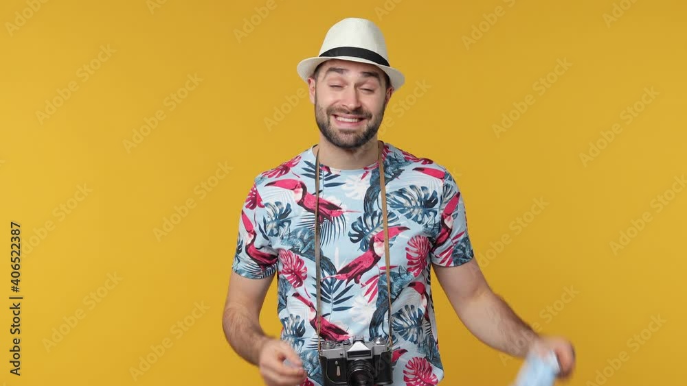Tired happy traveler tourist young man taking off face mask safe from coronavirus virus isolated on yellow background. Passenger travel on weekends. Air flight journey concept. Doing winner gesture Tired happy traveler tourist young man taking off face mask safe from coronavirus virus isolated on yellow background. Passenger travel on weekends. Air flight journey concept. Doing winner gesture