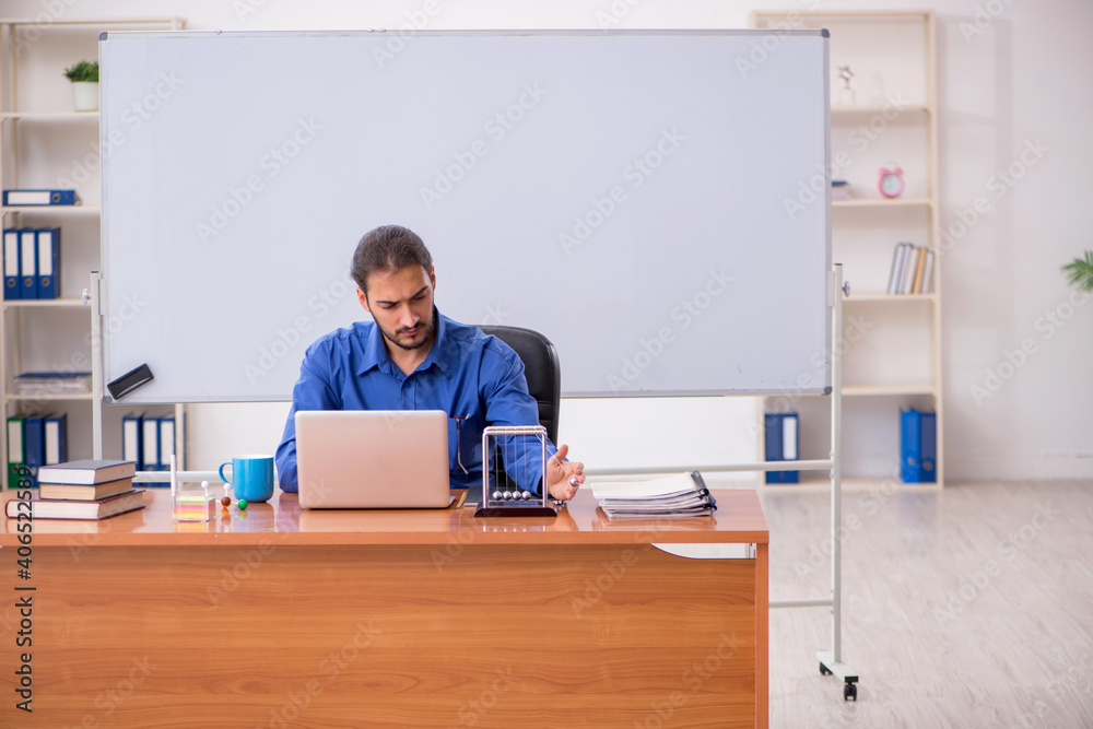Young male teacher physicist sitting in the classroom Young male teacher physicist sitting in the classroom