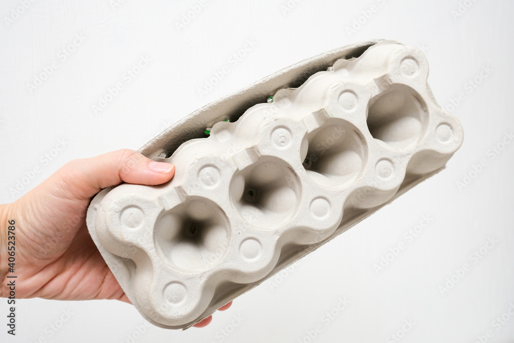 A hand holding recycled carton egg box container to protect egg shell of damage, package for fragile products A hand holding recycled carton egg box container to protect egg shell of damage, package for fragile products