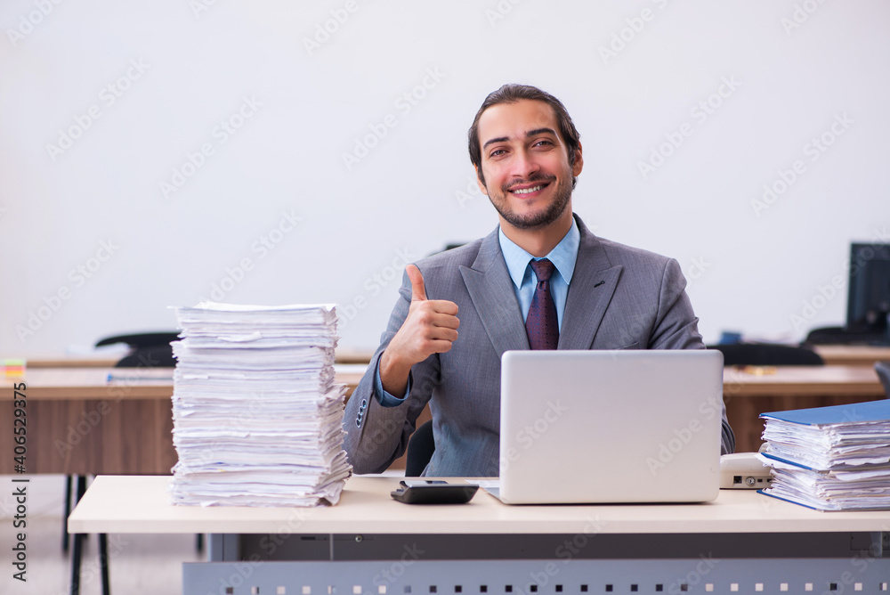 Young male employee unhappy with excessive work in the office Young male employee unhappy with excessive work in the office