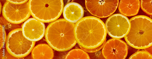 Citrus fruits slices assortment pattern background: orange, lemon and mandarin. Horizontal web banner. Slice of citrus flat lay texture.