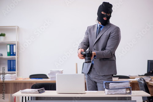 Young male employee in industrial espionage concept