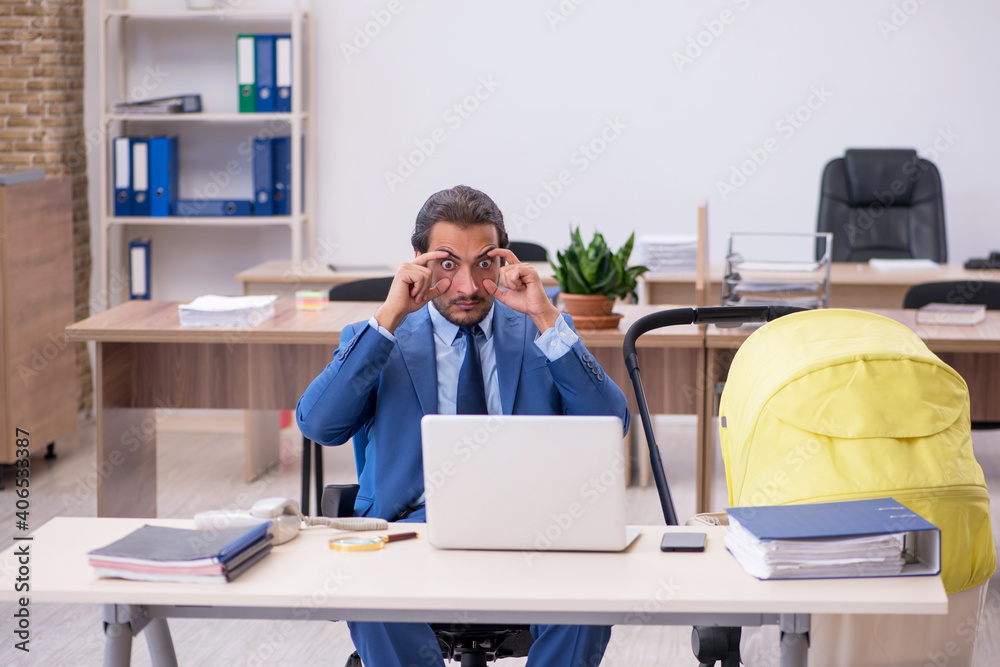 Young male employee looking after new born at workplace Young male employee looking after new born at workplace