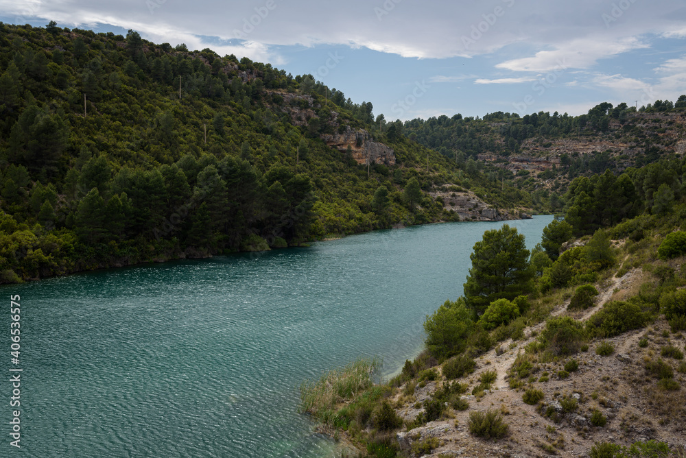 Quiet blue water river in the Alarcon sickles full of green trees on a cloudy day, Alarcon, Cuenca, Spain