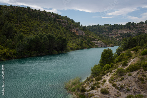 Quiet blue water river in the Alarcon sickles full of green trees on a cloudy day, Alarcon, Cuenca, Spain