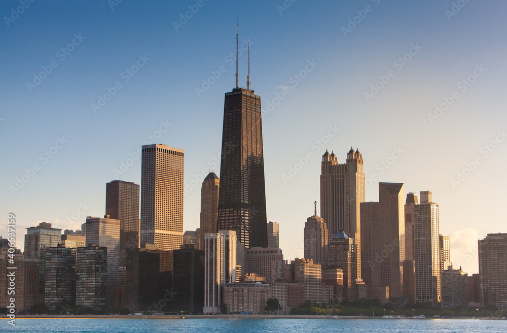 Fototapeta premium Chicago Illinois city sunset skyline and cityscape from Lake Michigan with John Hancock Building in the center. Evening light in the summer from sailboat at the playpen. 