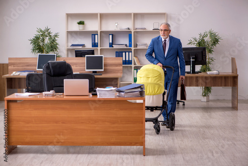 Aged businessman employee looking after newborn at workplace