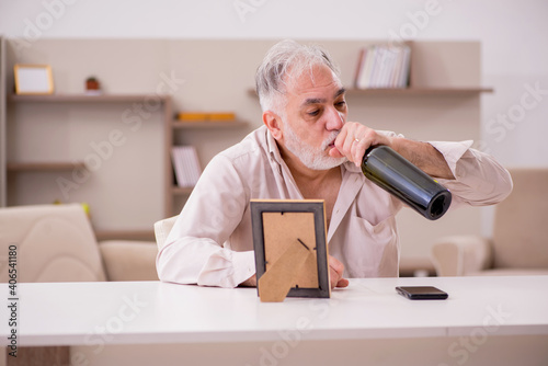 Old widower drinking alcohol at home