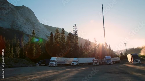 Rugged mountain peak and semi trailers next to Trans Canada highway at sunrise with a truck stop. 4K 24FPS. photo