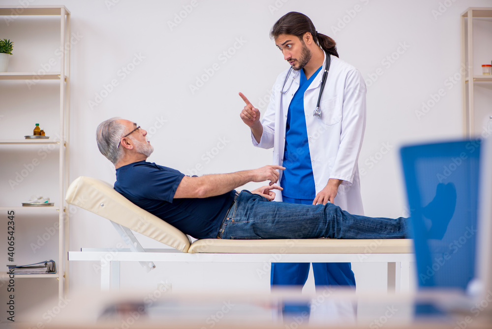 Obraz premium Old male patient visiting young male doctor chiropractor