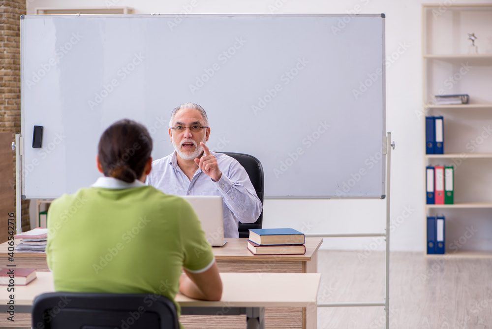 Old male teacher and young male student in the classroom