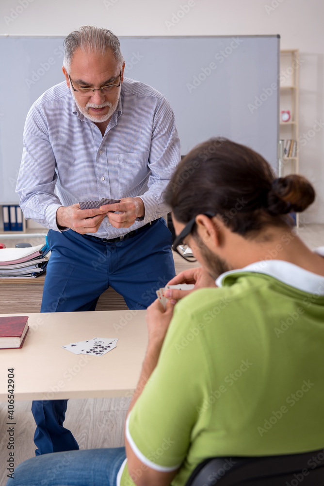 Obraz premium Old male teacher and young male student playing card in the clas