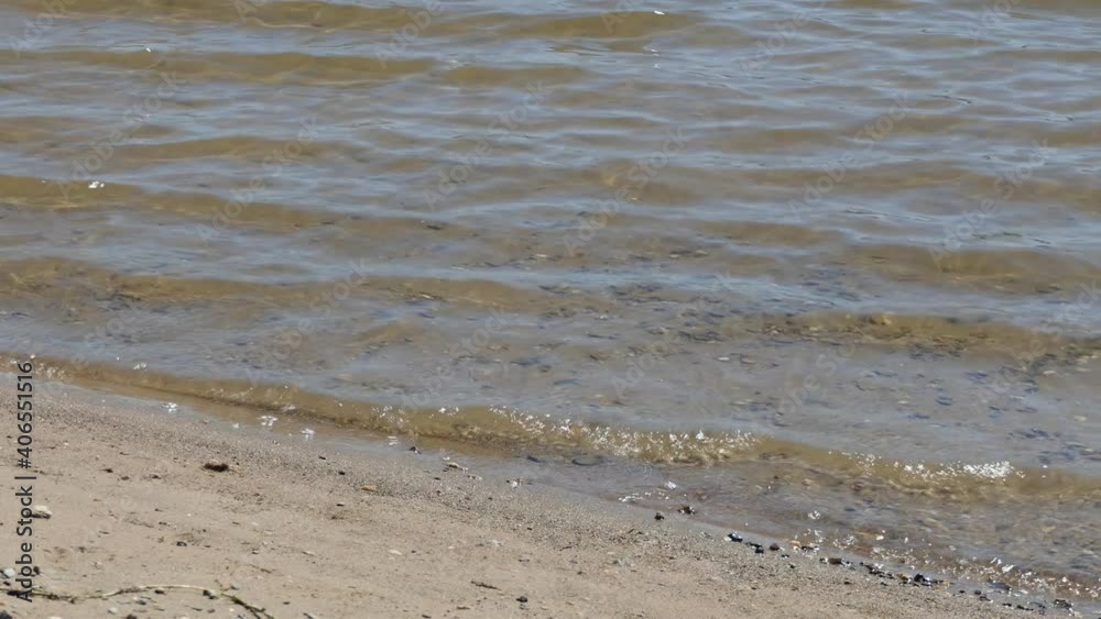 Surf on a sandy beach. Small waves roll on the shore of a sandy beach on a Sunny day. Close up. Surf on a sandy beach. Small waves roll on the shore of a sandy beach on a Sunny day. Close up.
