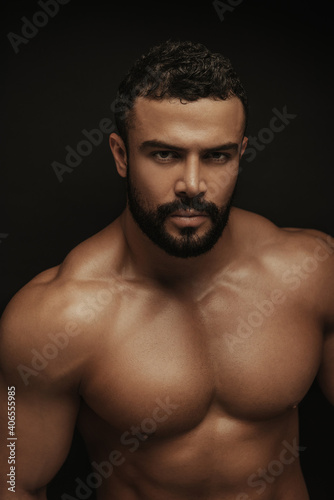 Poprtrait of Latin handsome shirtless man on black background