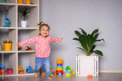 happy little one-year-old girl runs around playing in kindergarten, at home
